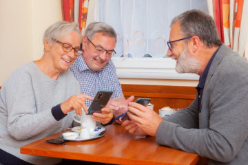 Drei ältere Personen mit Smartphones an einem Tisch